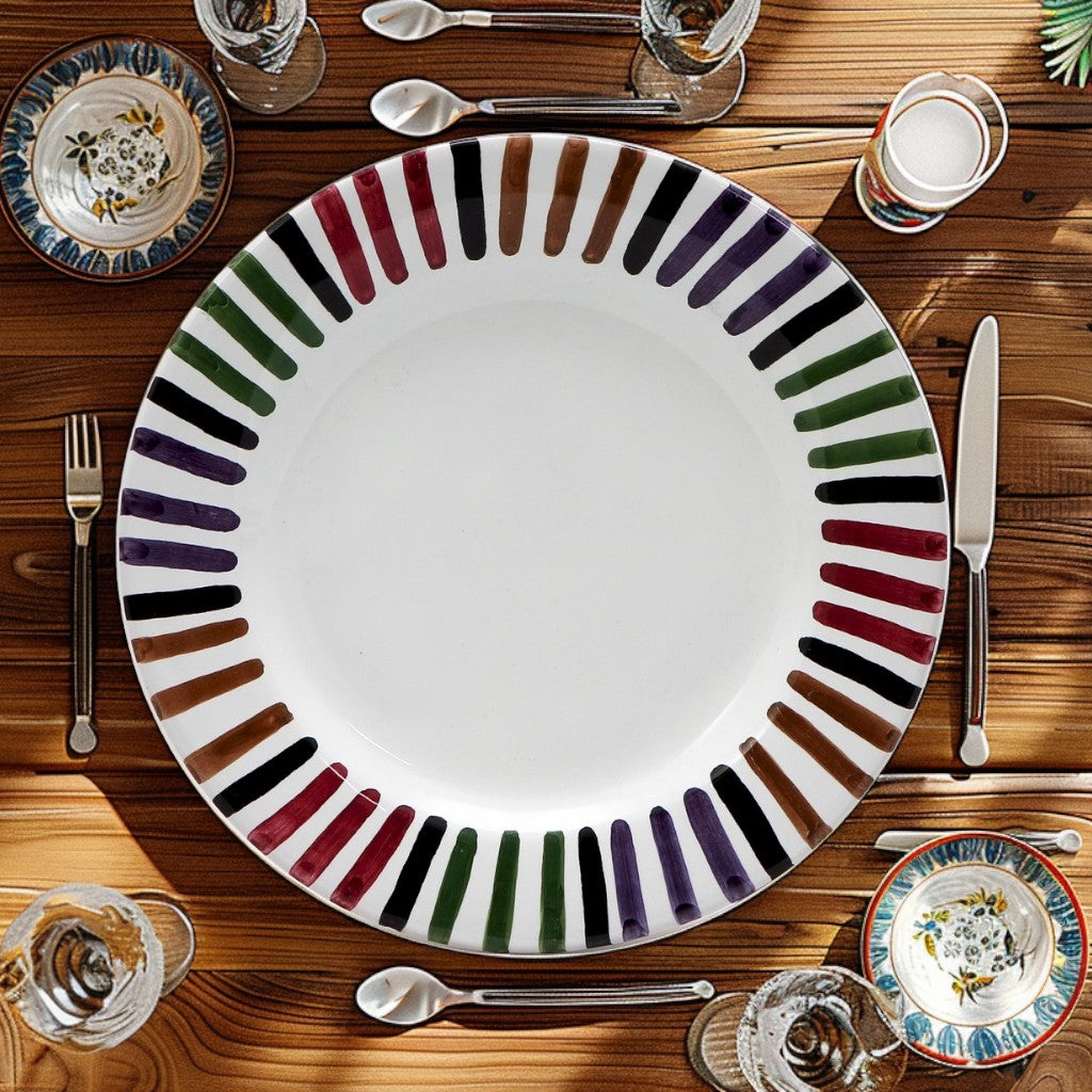 Top view of an elegant dining table set with the Hand-Painted BELLO Salad Plate by Bill Goldsmith for Deruta of Italy. The 8-inch ceramic plate features vibrant brush strokes in black, green, purple, brown, and red, highlighting Italian artisanal craftsmanship. Perfect for fine dining and special occasions.